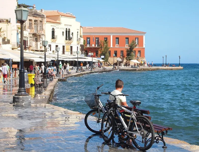 The waterfront promenade of Chania old harbour with cafes and a seaside bench