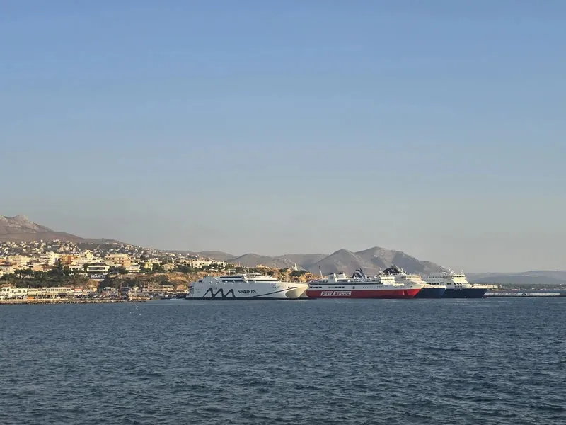 Several ferries lined up in a harbour beneath a hazy hillside town