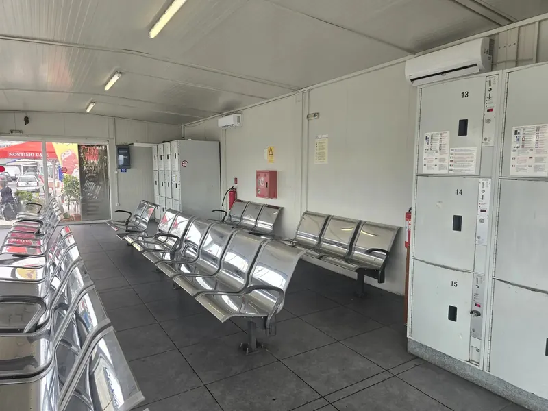 Grey luggage lockers and metal benches in a covered waiting area at a ferry port