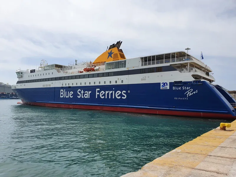 A Blue Star Ferries car ferry moored at a quay, its blue hull and yellow funnel clearly visible